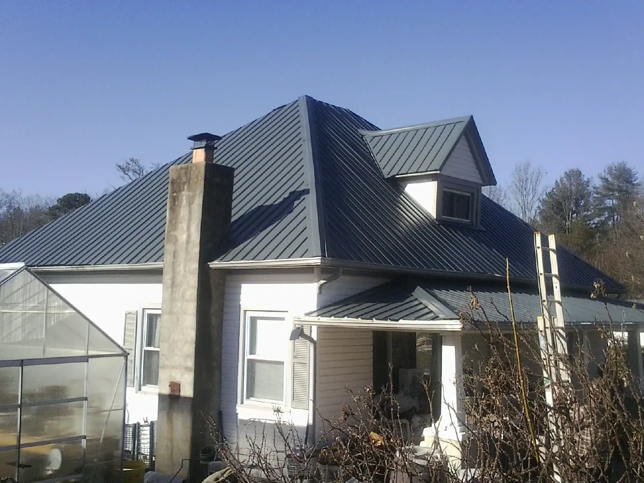 Dark blue standing seam metal roof on a white farmhouse with dormer — Slate & Tile Roof Repair by Roofing Brothers in Sherwood