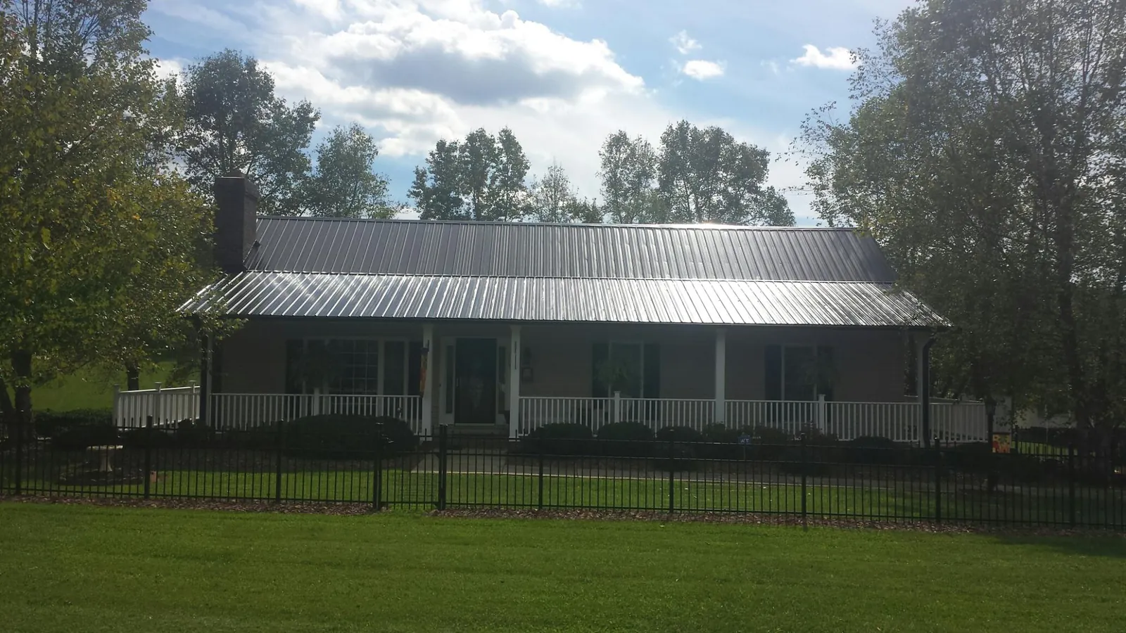 Gray metal roof on a brick ranch with a full width front porch in Sherwood